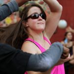 A woman in a pink tank top is about to turn in a dance turn